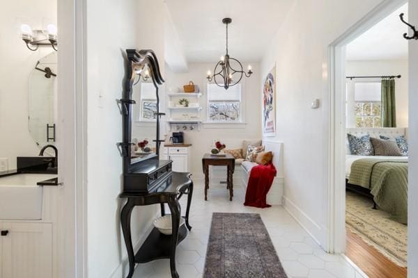 corridor with a notable chandelier, a sink, and baseboards