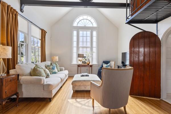 living area with lofted ceiling with beams, light wood-type flooring, plenty of natural light, and arched walkways