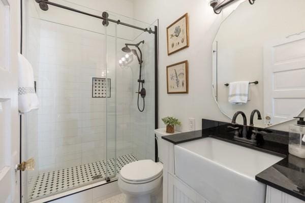 bathroom with a shower stall, toilet, and vanity