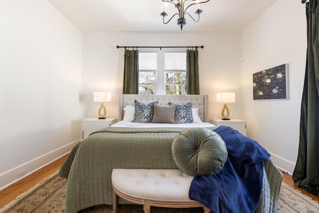 bedroom featuring a notable chandelier, baseboards, and wood finished floors