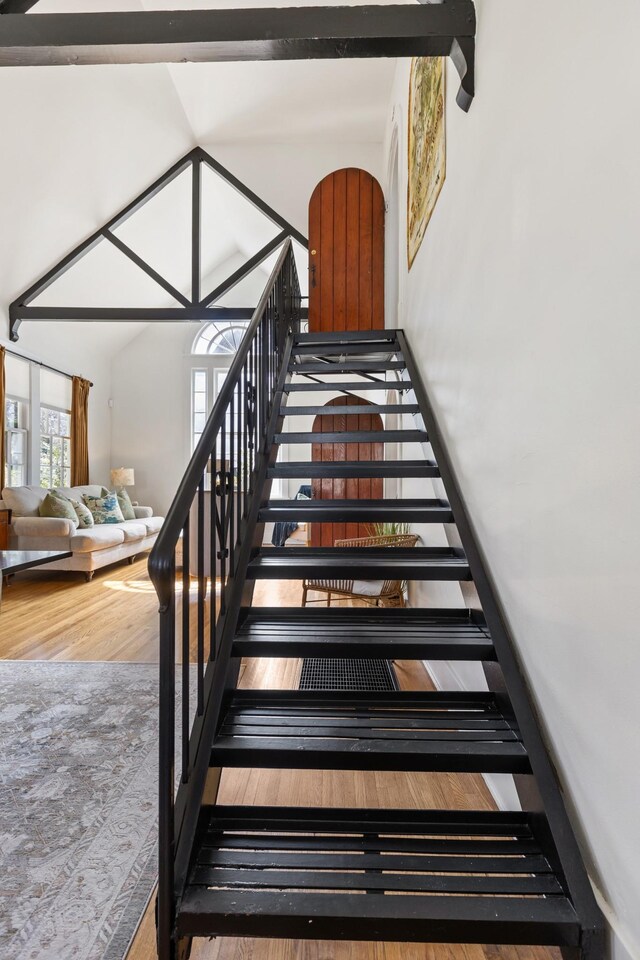 stairs featuring wood finished floors and a towering ceiling