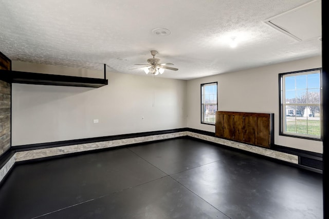 empty room with a textured ceiling, ceiling fan, and concrete floors