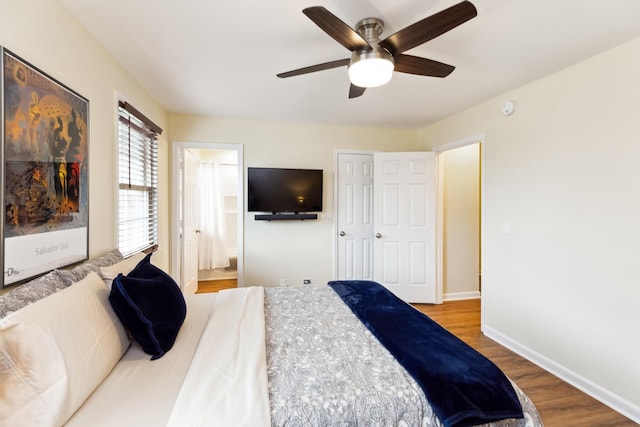 bedroom featuring a ceiling fan, ensuite bathroom, baseboards, and wood finished floors