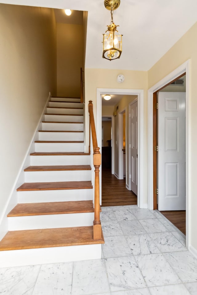 stairway with marble finish floor and baseboards