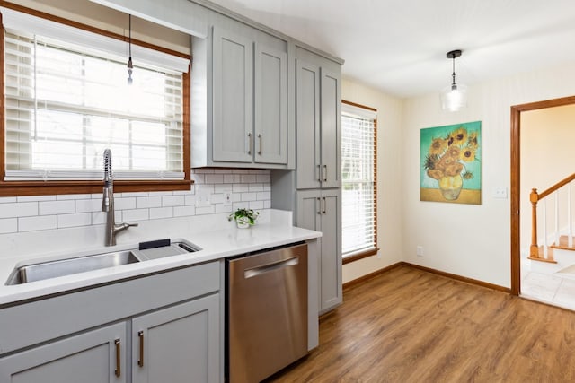 kitchen with dishwasher, a sink, gray cabinets, and decorative backsplash