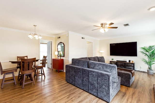 living room with light wood finished floors, baseboards, ornamental molding, and ceiling fan with notable chandelier