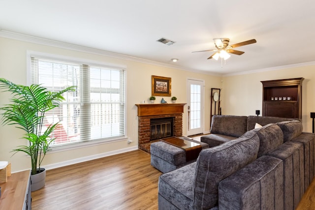 living area with a fireplace, wood finished floors, visible vents, baseboards, and ornamental molding