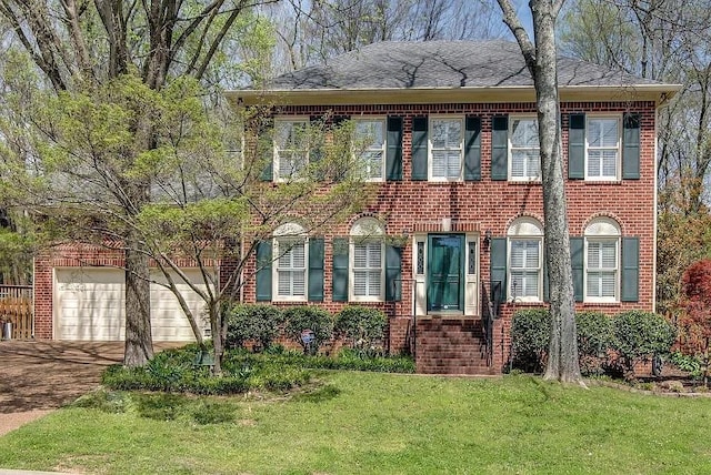 colonial home with a garage, driveway, a front lawn, and brick siding