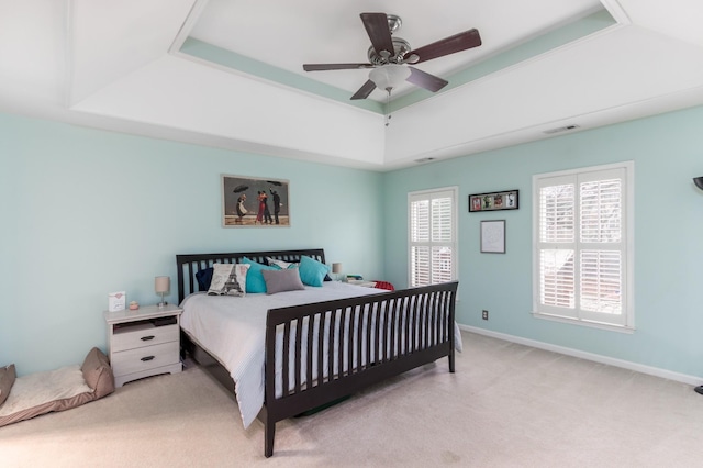 bedroom with carpet, a raised ceiling, visible vents, a ceiling fan, and baseboards