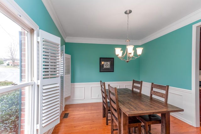 dining space featuring a chandelier, a wainscoted wall, visible vents, and light wood-style flooring