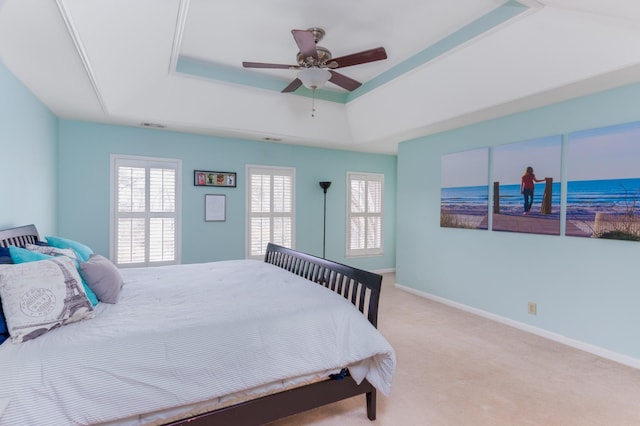 carpeted bedroom with ceiling fan, a raised ceiling, visible vents, and baseboards