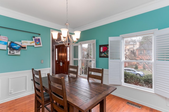 dining room featuring light wood-style floors, visible vents, a chandelier, and ornamental molding