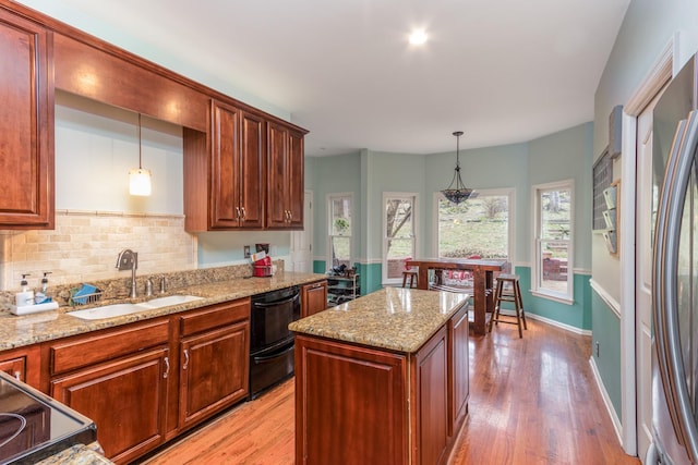 kitchen featuring tasteful backsplash, a sink, light wood-style flooring, and decorative light fixtures