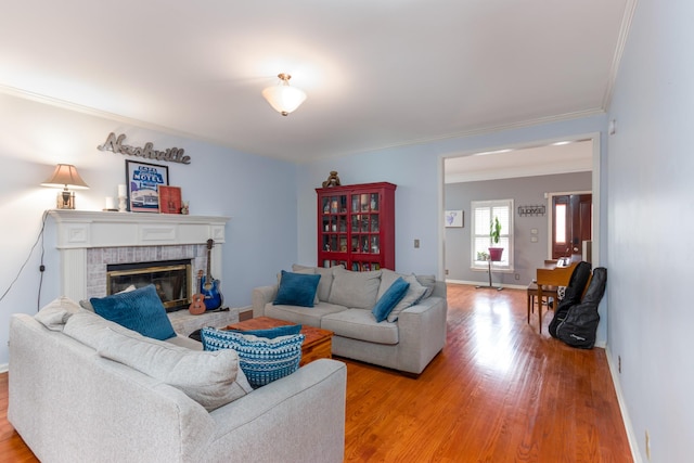 living room with baseboards, a brick fireplace, light wood-style flooring, and crown molding