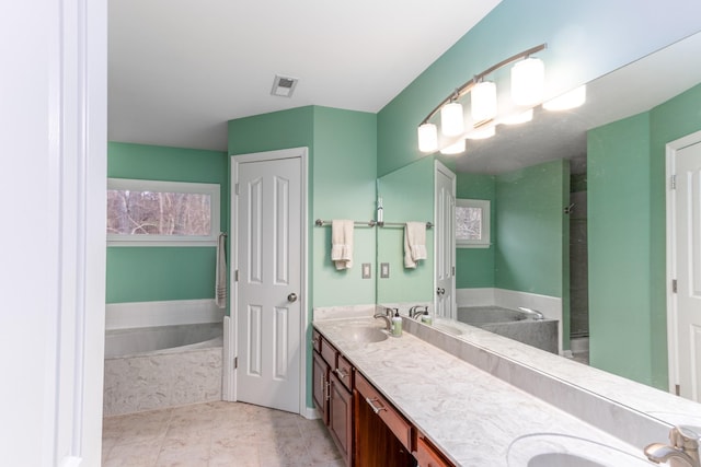 full bathroom with a sink, a bath, and double vanity