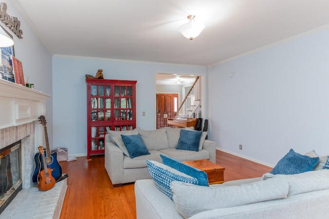 living room featuring crown molding, wood finished floors, a fireplace, and stairs