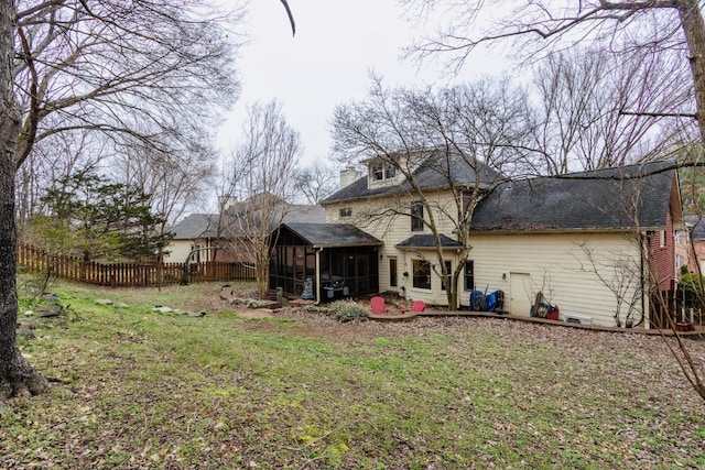 rear view of house with a yard, fence, and a sunroom