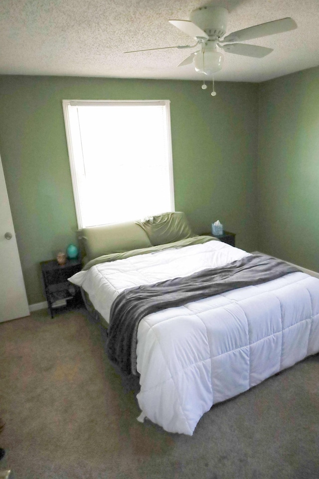 bedroom with a textured ceiling, carpet, and a ceiling fan