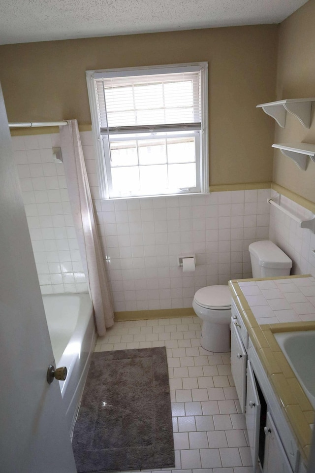 full bath featuring a textured ceiling, tile patterned flooring, toilet, vanity, and tile walls