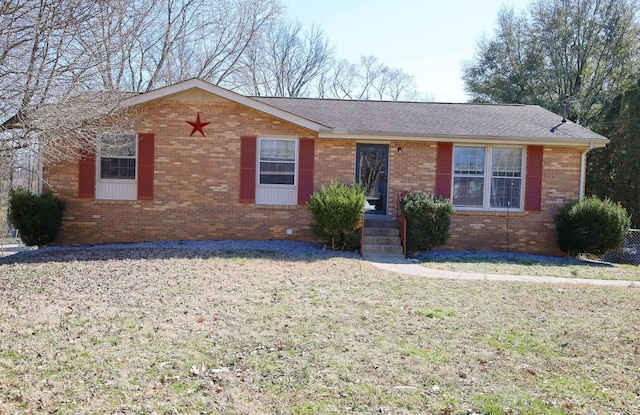 ranch-style home with brick siding, a front yard, and a shingled roof