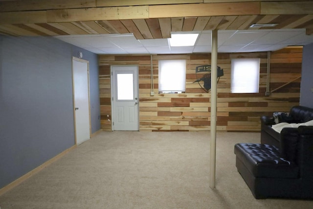 basement with carpet floors, visible vents, wood walls, and baseboards