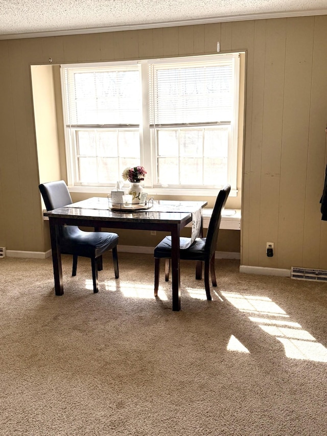 dining room with a textured ceiling, ornamental molding, and carpet flooring