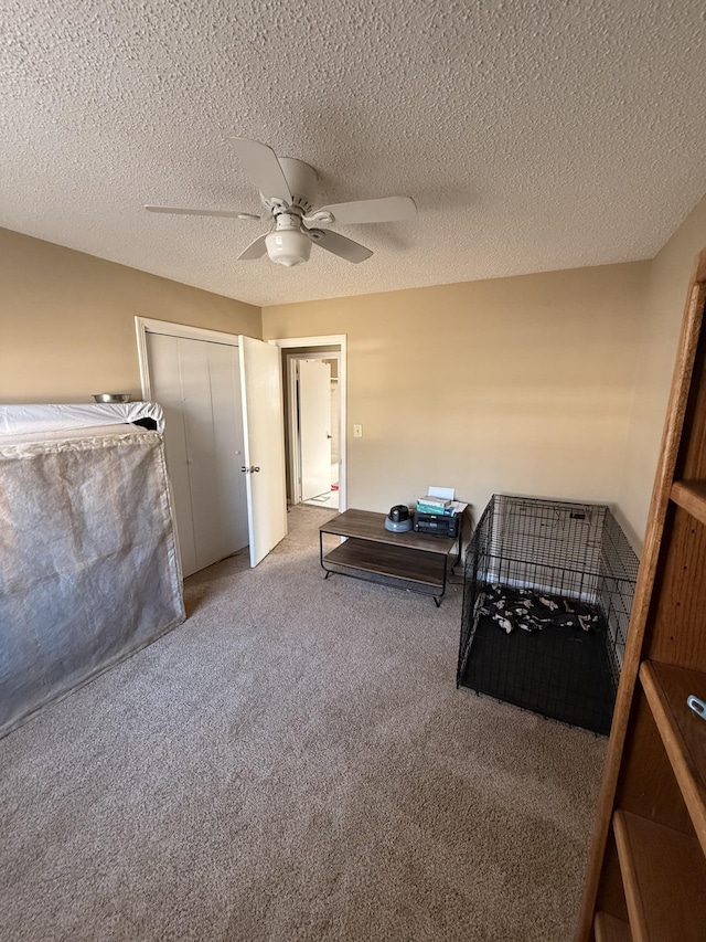 bedroom featuring light carpet, a closet, a textured ceiling, and a ceiling fan