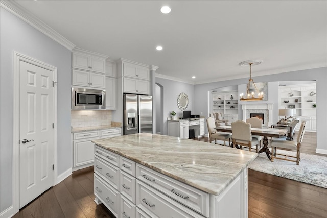 kitchen with ornamental molding, dark wood-style flooring, light stone countertops, stainless steel appliances, and white cabinetry