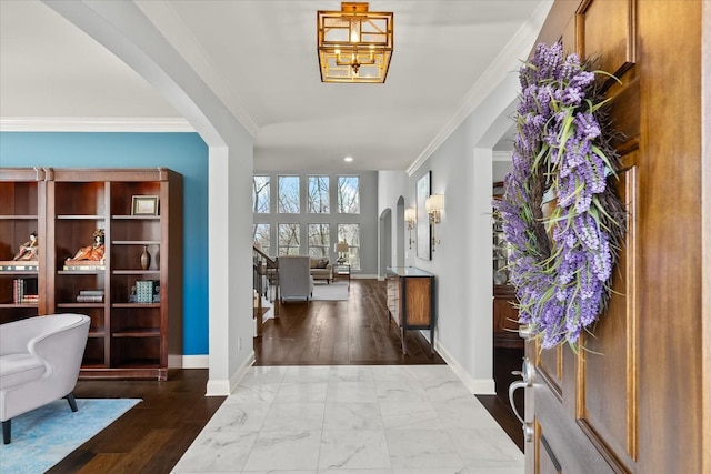 entryway with arched walkways, marble finish floor, baseboards, and crown molding