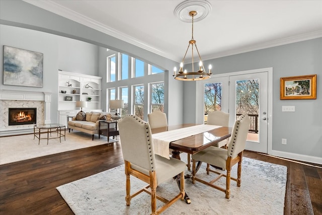 dining area with a premium fireplace, plenty of natural light, wood finished floors, and crown molding