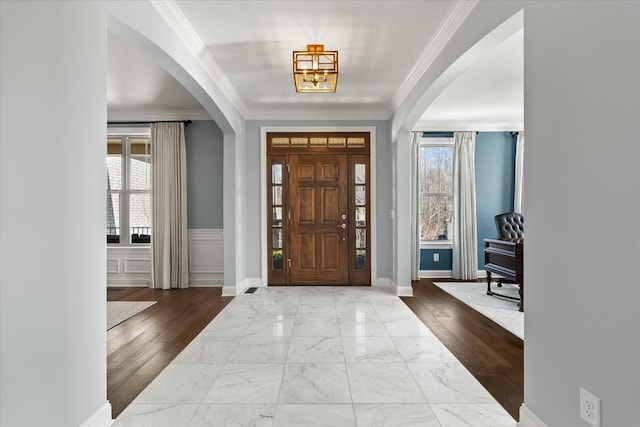 foyer with a wealth of natural light, marble finish floor, and arched walkways