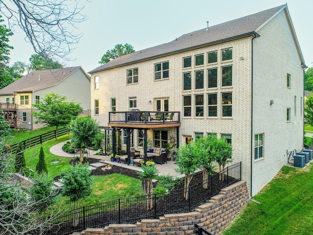 rear view of property featuring brick siding, a lawn, a patio area, and an outdoor living space