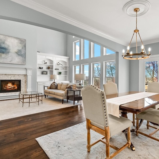 dining space with a notable chandelier, a fireplace, ornamental molding, and wood finished floors