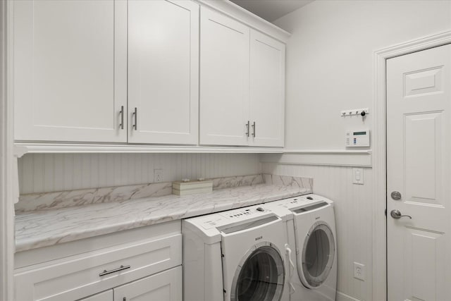 washroom featuring cabinet space, wainscoting, and independent washer and dryer