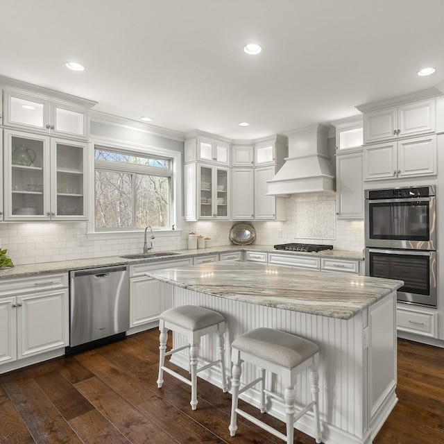 kitchen with stainless steel appliances, dark wood-type flooring, a sink, white cabinets, and custom range hood