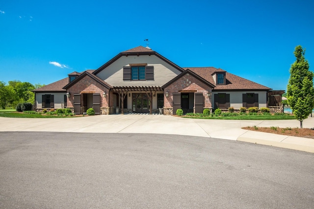 view of front of home with brick siding and a pergola