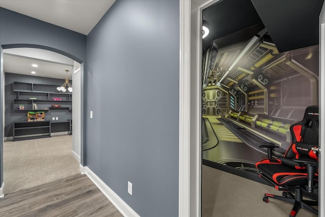 hall with arched walkways, wood finished floors, and baseboards