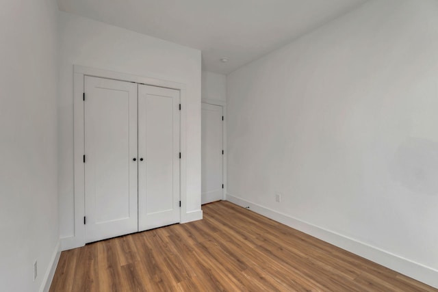 unfurnished bedroom featuring a closet, baseboards, and wood finished floors