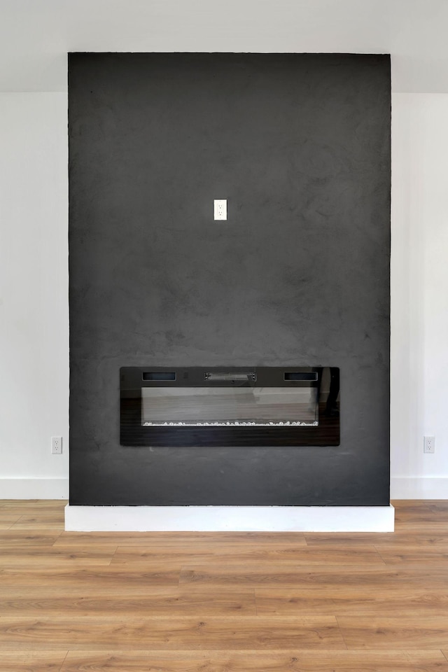 interior details featuring a large fireplace, wood finished floors, and baseboards