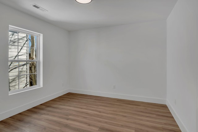 spare room with light wood-style flooring, visible vents, and baseboards