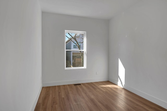 spare room with baseboards, visible vents, and wood finished floors