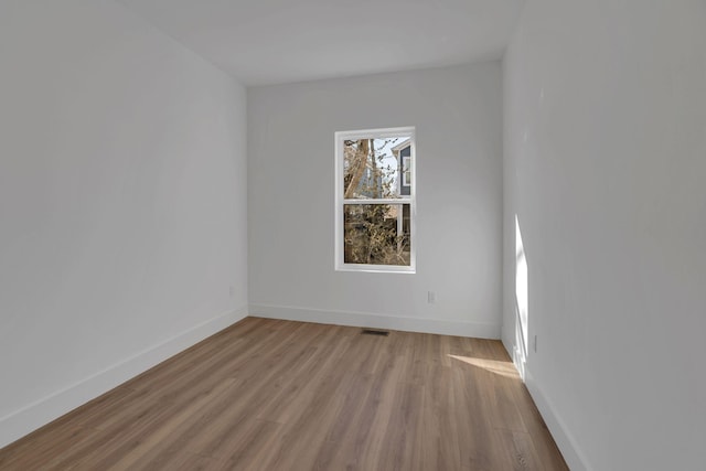 unfurnished room featuring visible vents, baseboards, and wood finished floors