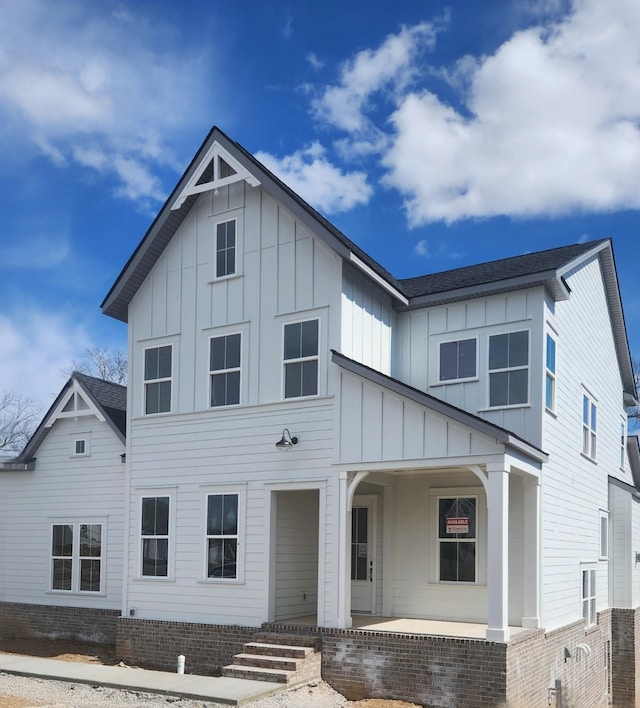 modern farmhouse style home with a porch, roof with shingles, and board and batten siding