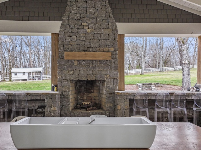 view of patio / terrace with fence and an outdoor stone fireplace