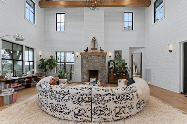 living area featuring wood walls, a fireplace, wood finished floors, and beam ceiling