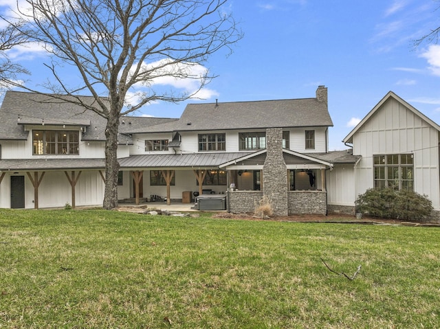 back of property with a patio, a chimney, a lawn, board and batten siding, and stone siding