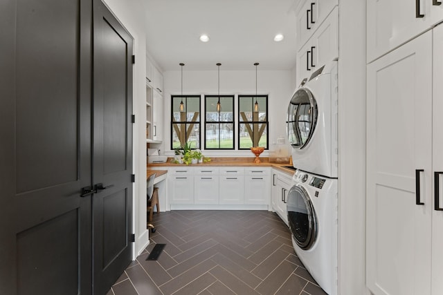 washroom with stacked washer and dryer, recessed lighting, and cabinet space