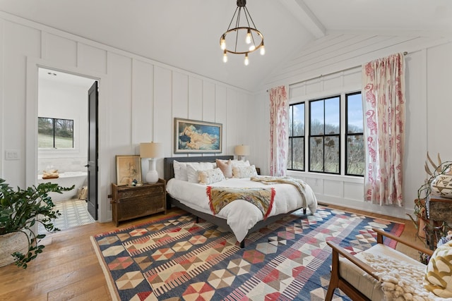 bedroom featuring multiple windows, a decorative wall, lofted ceiling with beams, and hardwood / wood-style flooring