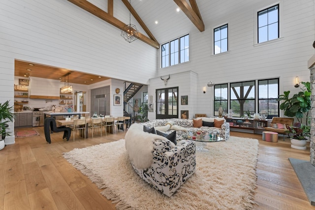 living room with high vaulted ceiling, light wood finished floors, and beam ceiling