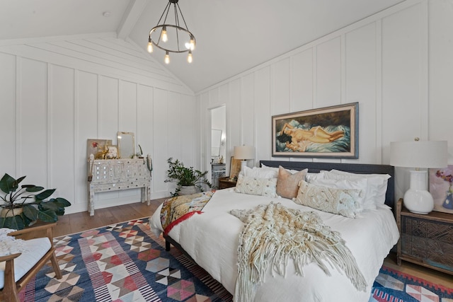 bedroom featuring a notable chandelier, vaulted ceiling with beams, a decorative wall, and wood finished floors